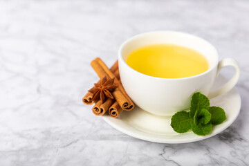 Fragrant hot tea with cinnamon stick and anise on a textured wooden background. A cup of hot tea...
