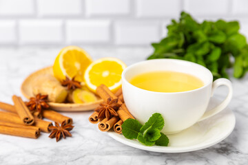 Fragrant hot tea with cinnamon stick and anise on a textured wooden background. A cup of hot tea with honey, lemon, mint and apples. Spicy tea with spices. Immunity tea. Health concept.Copy space.