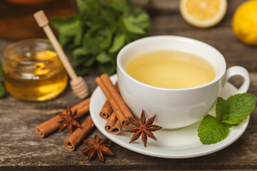 Fragrant hot tea with cinnamon stick and anise on a textured wooden background. A cup of hot tea...