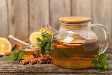 Fragrant hot tea with cinnamon stick and anise on a textured wooden background. A teapot brewing...