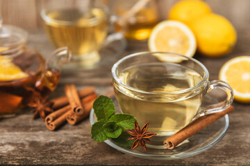 Fragrant hot tea with cinnamon stick and anise on a textured wooden background. A cup of hot tea with honey, lemon, mint and apples. Spicy tea with spices. Immunity tea. Health concept.Copy space.
