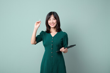 Happy asian woman smile and holding tablet isolated on light green background