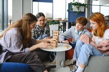 The company of young people plays a table game called jenga