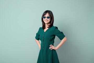 An Asian woman green dress holding hips isolated on pastel green background.