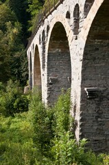 Fototapeta premium Old stone railway bridge with arches made of natural stone in the Thuringian Slate Hills, Germany