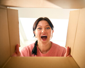 View Looking Up At Young Excited Woman Opening Cardboard Box