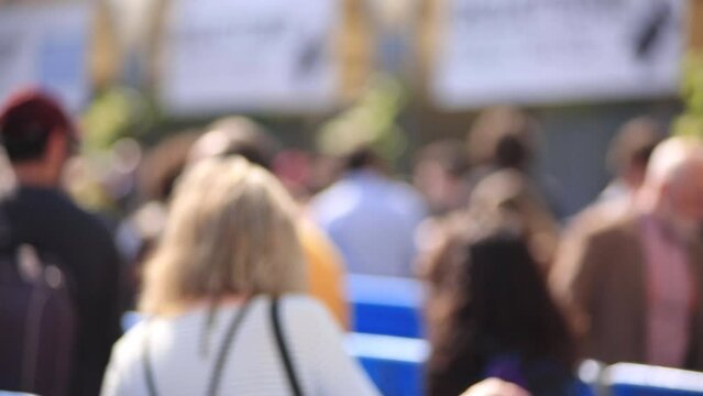 persone sfocate  in coda che camminano in attesa di entrare ad un evento ,fiera ,ripresa di spalle con transenna