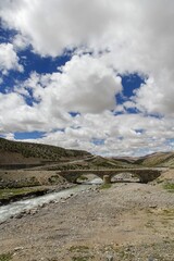 Vertical of a bridge on a river in a barren landscape on a cloudy day