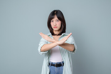 serious asian woman shows cross hands gesture, stop sign, taboo, disapproves bad action, stands in...