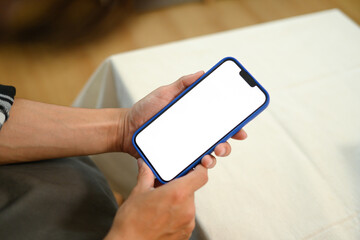 Unrecognizable man hands holding mobile phone with empty screen sitting on couch