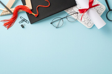 E-learning celebration idea. Top view of pc keyboard, cap, diploma, study materials, glasses on...
