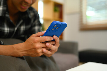 Close up shot of smiling man scrolling news in social media on mobile phone