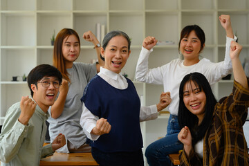 Group of happy university students and mature professor celebrating success in the classroom