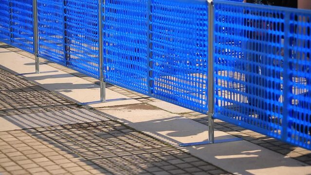 persone in coda che camminano in attesa di entrare ad un evento ,fiera ripresa attraverso una transenna 