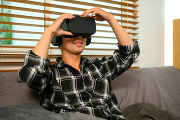 Young man virtual reality headset sitting on couch in living room