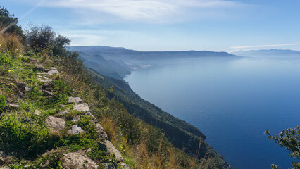 Obraz premium Tyrrhenian Sea bay seen from Monte Sant'Elia viewpoint during daytime with smoke rising up from active Etna volcano at Sicily, Palmi, Calabria, Italy