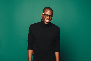 Confident African man laughing while standing against green background