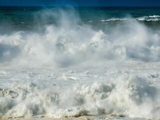 a surfer walking away from the ocean with his board under the waves