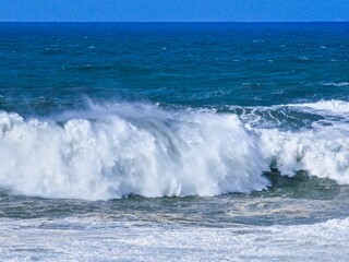 a large wave is rolling toward the shore as surfers watch