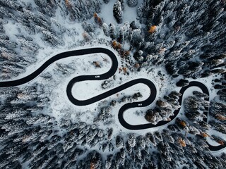 Aerial shot of a winding road cutting through a wintery snowy Italien landscape © Wirestock