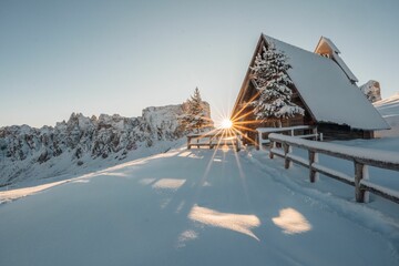 Idyllic rural landscape featuring a wooden cabin with a sunlit Italien mountains