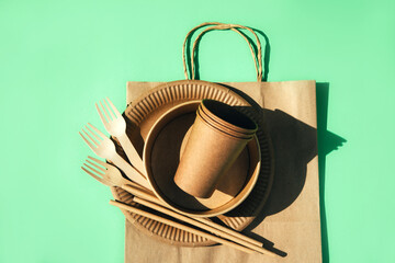 A set of paper utensils, wooden cutlery on paper bag on a green background. Eco friendly, zero...