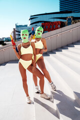 Two beautiful sexy women in green underwear. Models wearing bandit balaclava mask. Hot seductive...