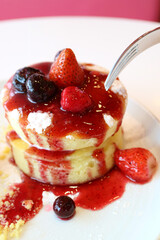 Closeup of mouthwatering chiffon cake with strawberry and blueberry sauce