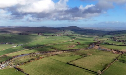 Aerial view of a rural countryside under a bright sky in New Cumnock, Scotland