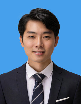 青い背景にスーツ姿の若い日本人男性の証明写真。バストアップ。