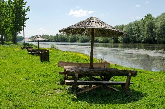 Scenic outdoor setting featuring parasols and benches by the river Bosut