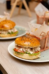 a wooden table topped with two plates filled with sandwiches and buns