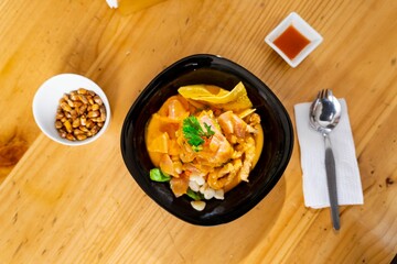 a plate of noodles and sauce sits on a table with a small spoon