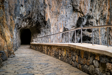 Walk through Túnel Sa Calobra tunnel, a tranquil passage carved through the cliff, connecting Sa Calobra to Torrent de Pareis canyon, ideal for showcasing travel adventures and outdoor exploration.