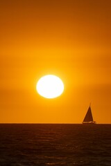 a sailboat on the water at sunset with yellow clouds