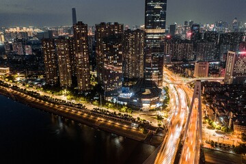 Naklejka premium Night view aerial shot of a group of tall buildings along the Han River in Wuhan.