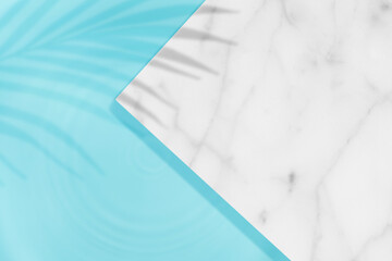 Swimming pool top view background with palm leaves shadow on marble table top and blue water ring...