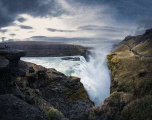 people are standing by the edge of a cliff with water flowing from it