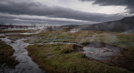 a stream running through the ground near a marsh with steam coming from it