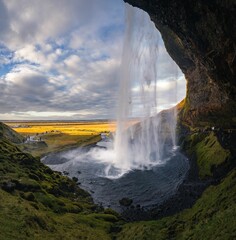 a waterfall flowing out of a cave into a river below