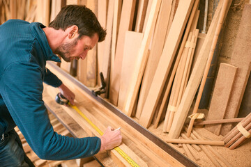 Carpenter Working In Woodwork Workshop Measuring Wood For Project
