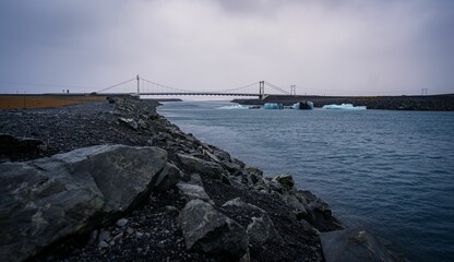 an iceberg is sitting in the water by a bridge