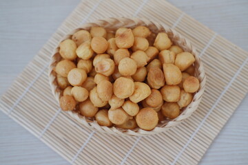 Crispy fried macadamia nuts in basket on wooden table