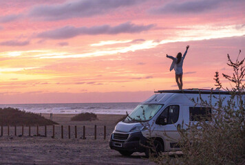 Happy person on camper van roof, embracing sunset by the sea, capturing the essence of travel...
