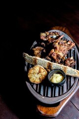 Close-up of a plate containing savory garlic, bread and juicy cooked meat