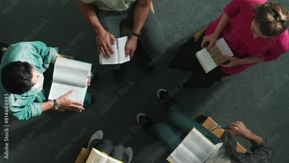 Wall mural Top down view of prayer reading at bible book and sitting in circle with bible book on laps. Aerial view of diverse people looking at book while studying with faith, trust and hope, calm. Symposium.