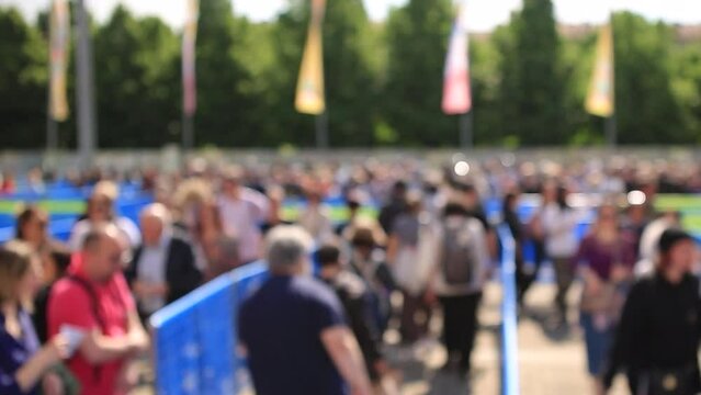 persone sfocate  in coda che camminano in attesa di entrare ad un evento ,fiera, ripresa molto larga 