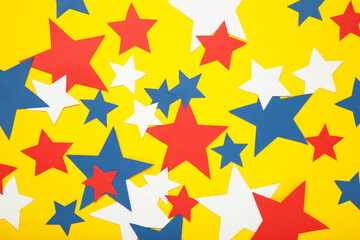 American independence day, celebration, patriotism and holidays concept - red, white and blue paper stars on yellow background.