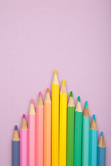 Pastel color pencils on purple background. Vertical photo