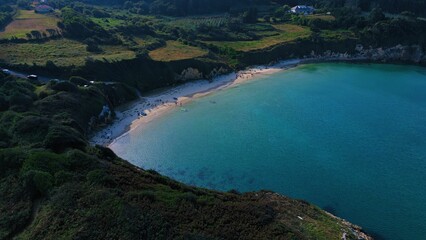 Scenic view of a beach from a cliff overlooking the ocean, azure blue water of the ocean